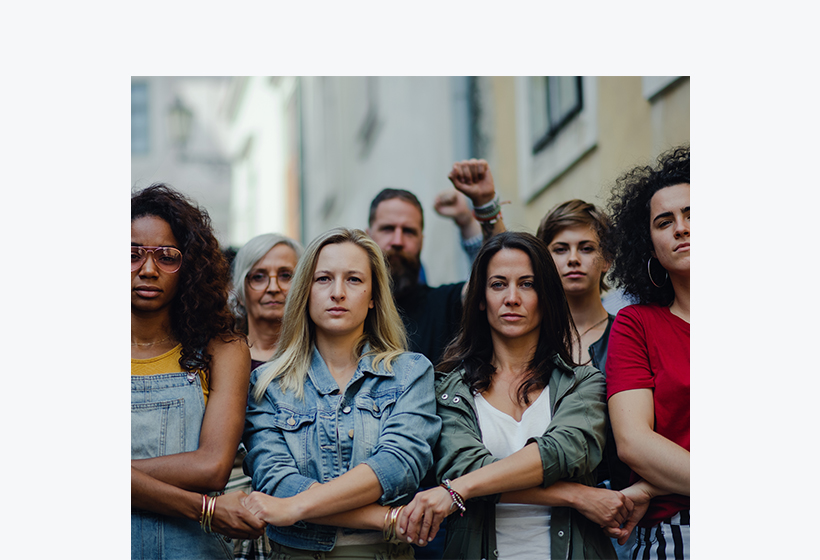 des adultes manifestant et se tenant pas les mains avec un air déterminé