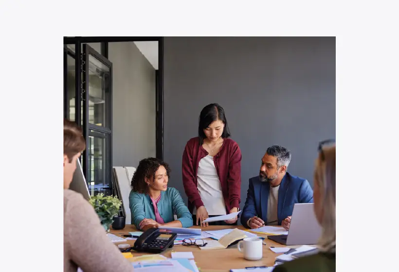 un groupe d'adultes autour d'une table sur laquelle se trouve notamment des dossiers ouverts