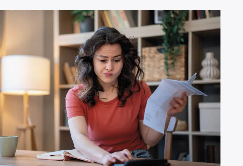 jeune femme gérant son budget avec calculatrice et doc à la main